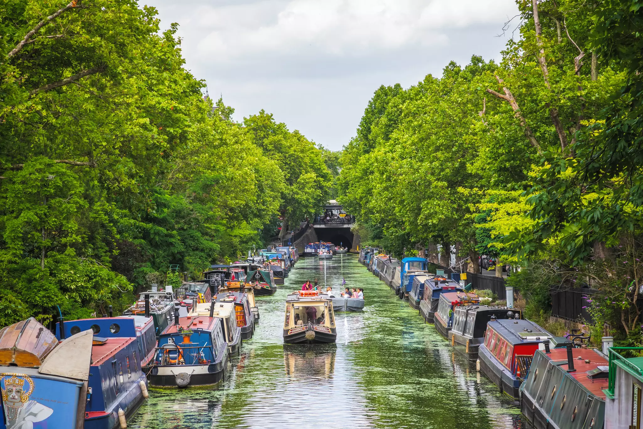 Boaters on a tree-lined canal on a sunny day. 