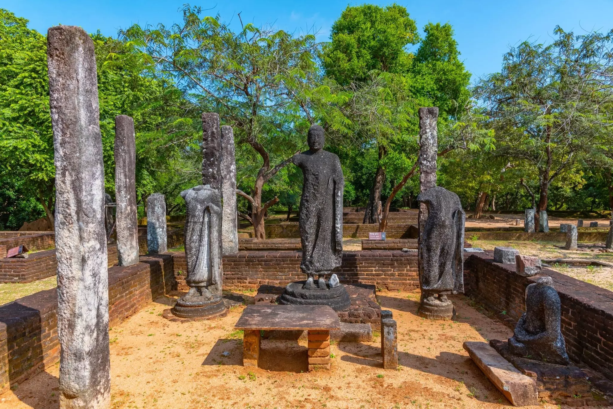 Ancient stone ruins resembling human figures and stone pillars at Polonnaruwa, Sri Lanka