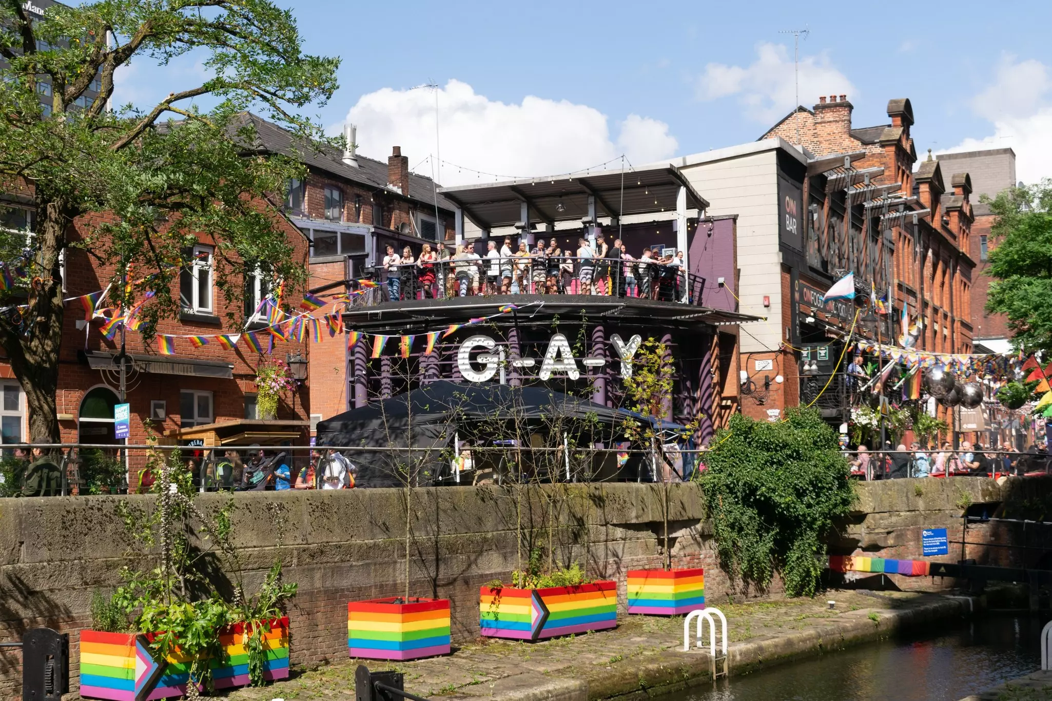 People on a balcony on a sunny day in a gay village with many rainbow motifs