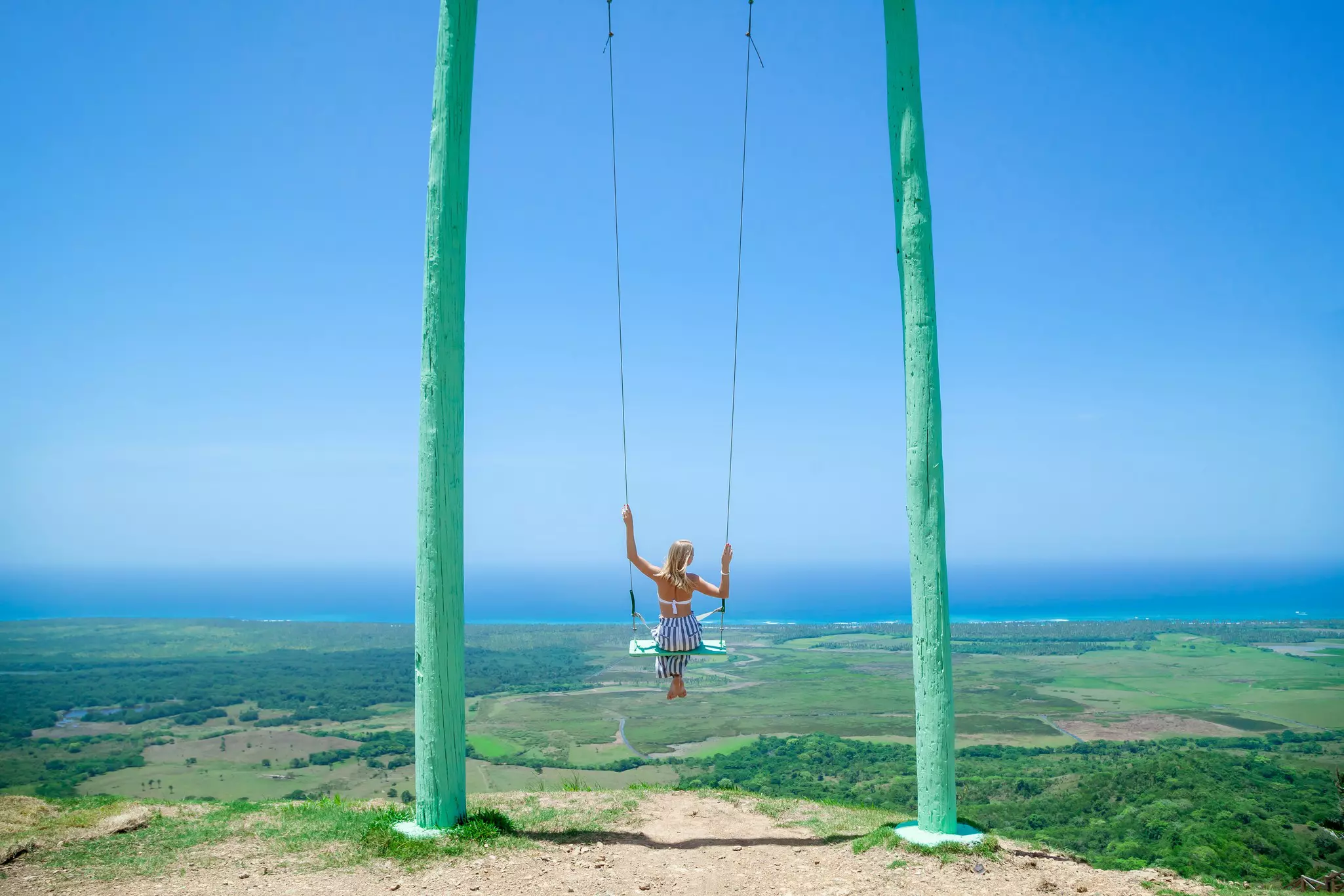 Woman swinging on swing over Montana Redonda, Dominican Republic