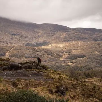 Landscape of Killarney National Park, Kerry, Ireland. Two people standing on hill and looking out.