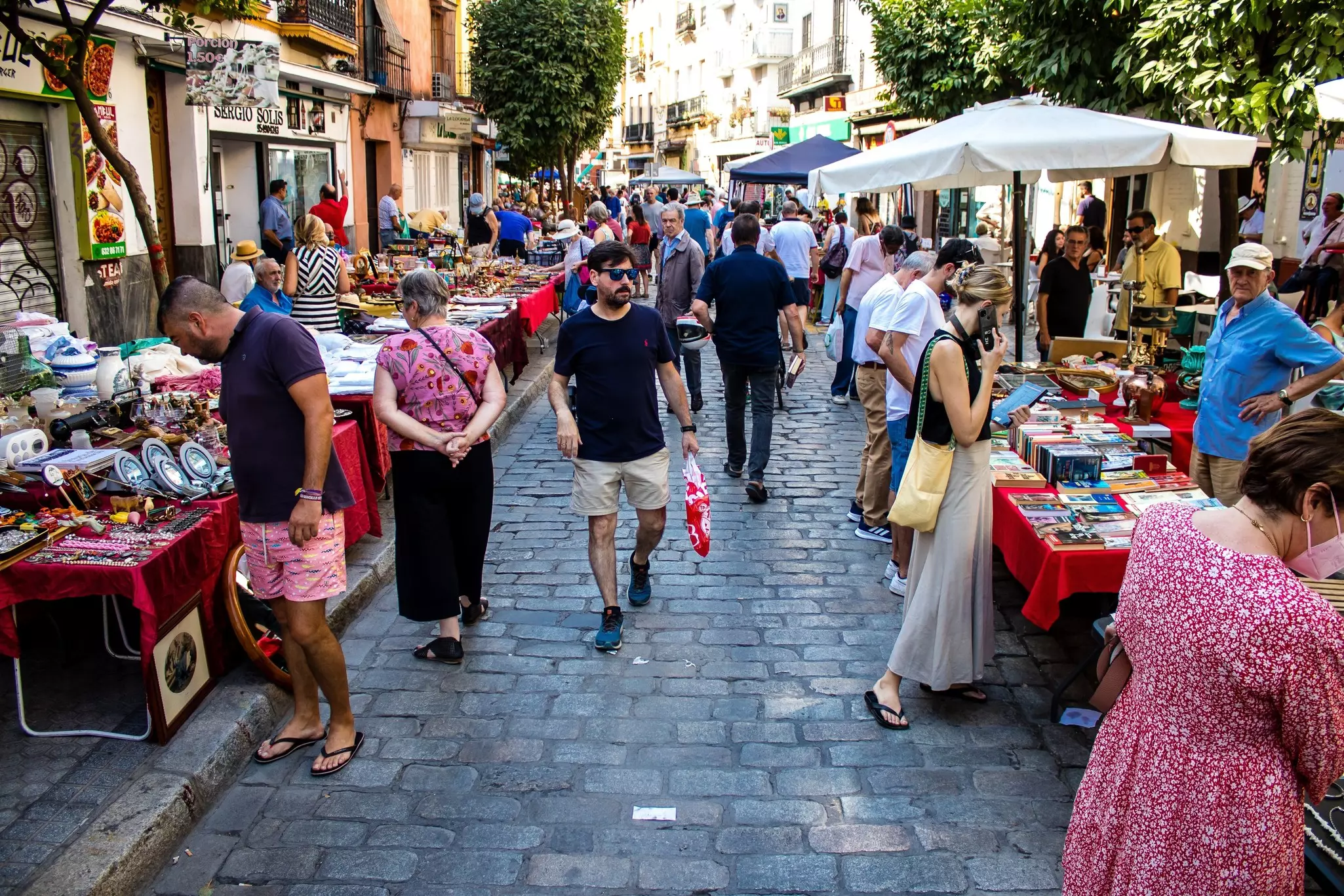 People walk by stalls set up in a city street for a flea market.
