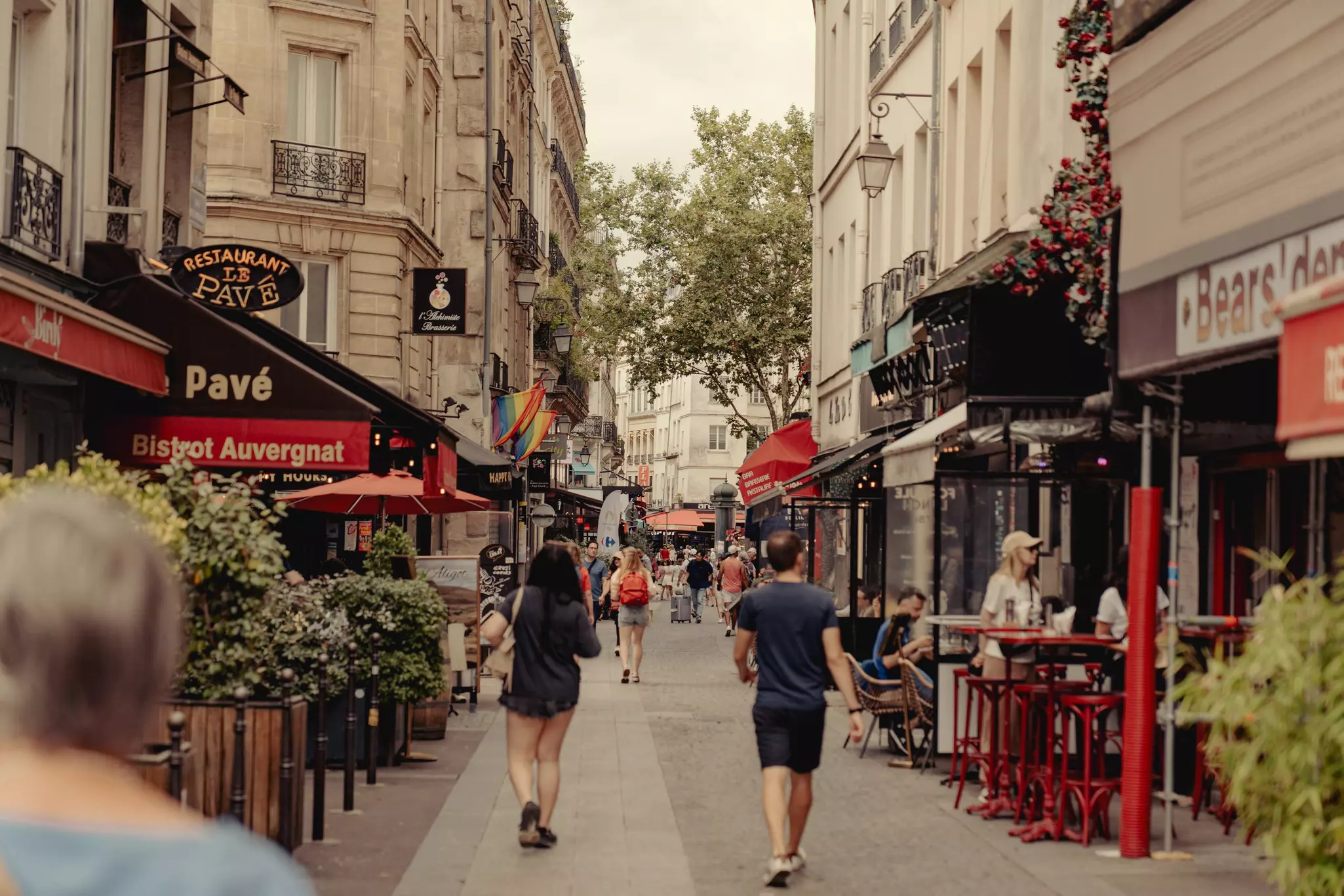 People wander down a pedestrianized street lined with bars and cafes