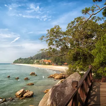Stunning nature of Kuantan. Best Kuantan beach resorts famous for pristine nature. Coastline with tropic nature plants sand beaches. Bridge or wooden pier at sea lagoon with rocks and waves.