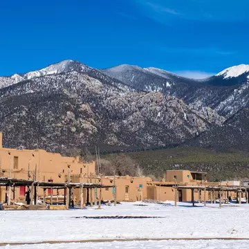 Low-rise red square buildings on a plateau at the foot of a snow-capped mountain range