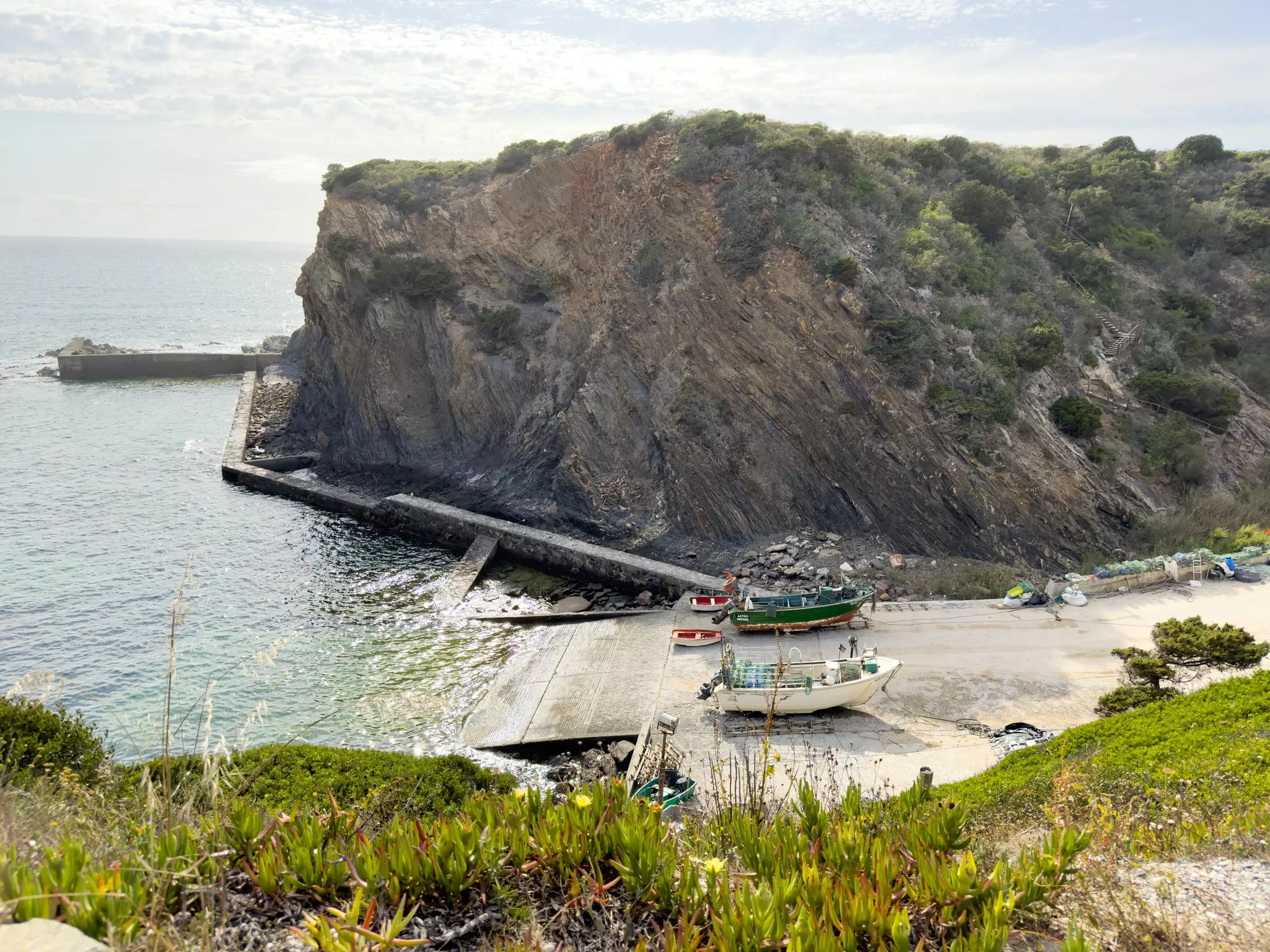 Small fishing boats at a sheltered harbor surrounded by cliffs.