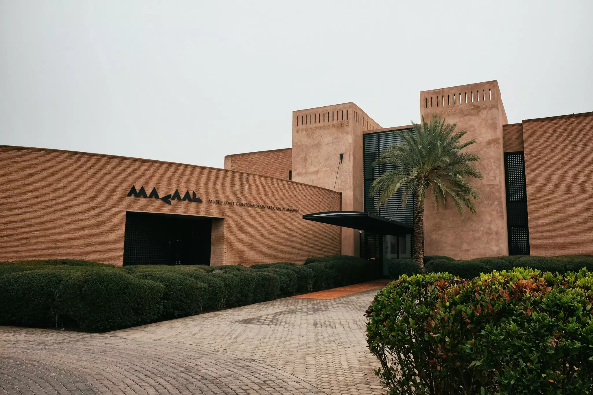 The exterior of a museum with a large stylized sign with the letters MACAAL.
