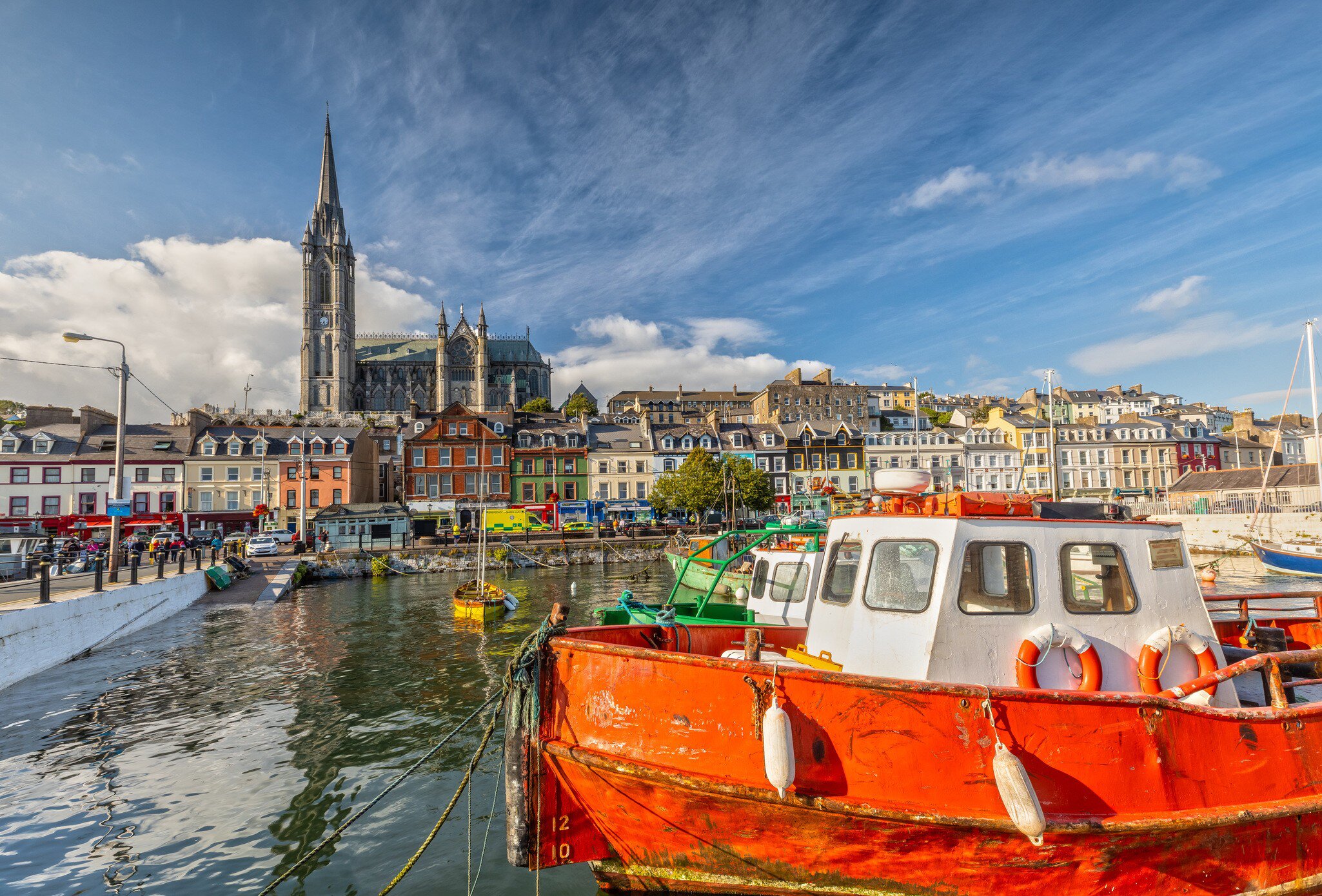Boats, colourful waterfront buildings and St. Colman's Cathedral in Cobh, Cork, Ireland.