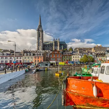 Boats, colourful waterfront buildings and St. Colman's Cathedral in Cobh, Cork, Ireland.