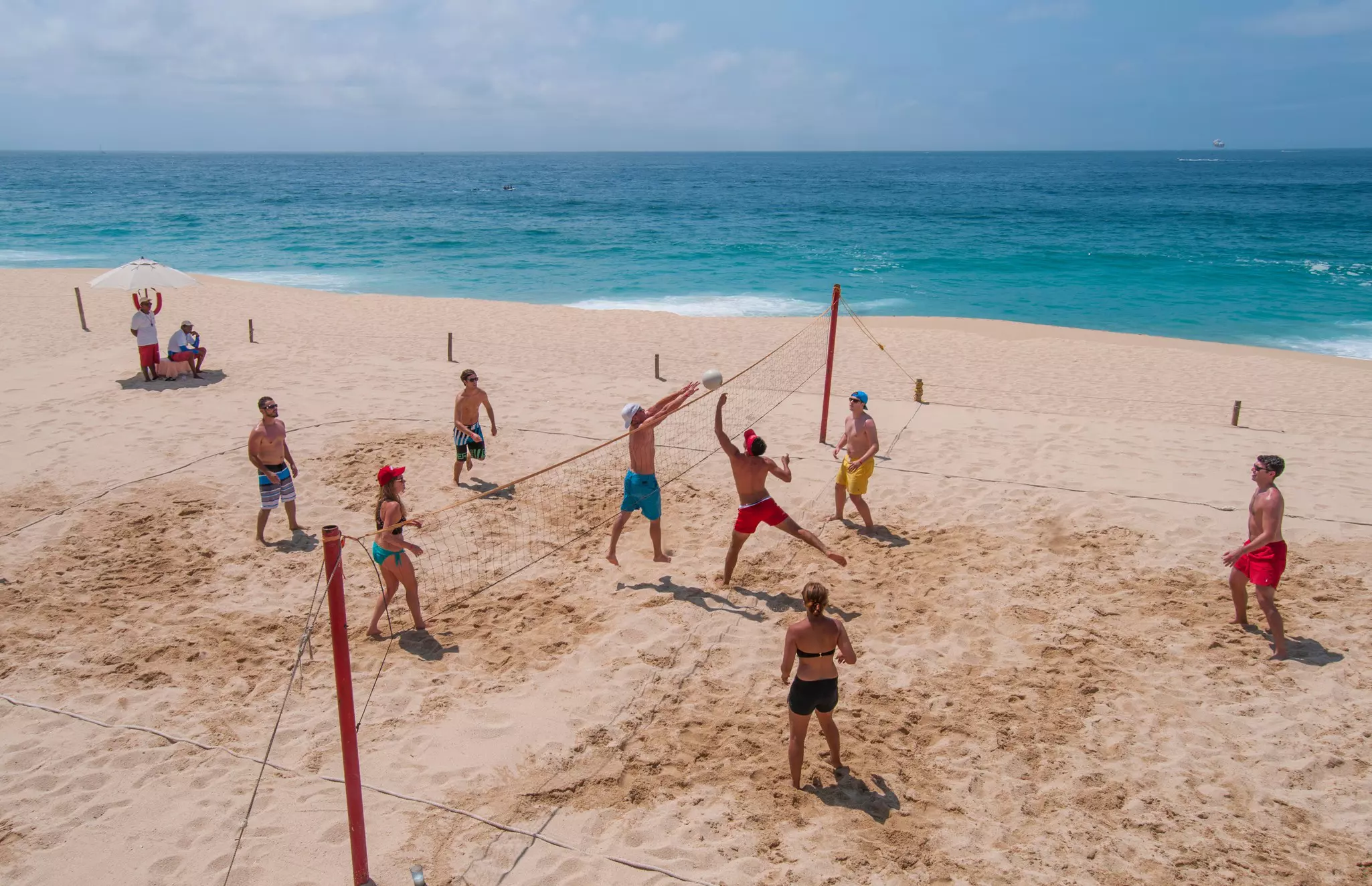 Young people playing bolley ball on the beach by the pacific ocean