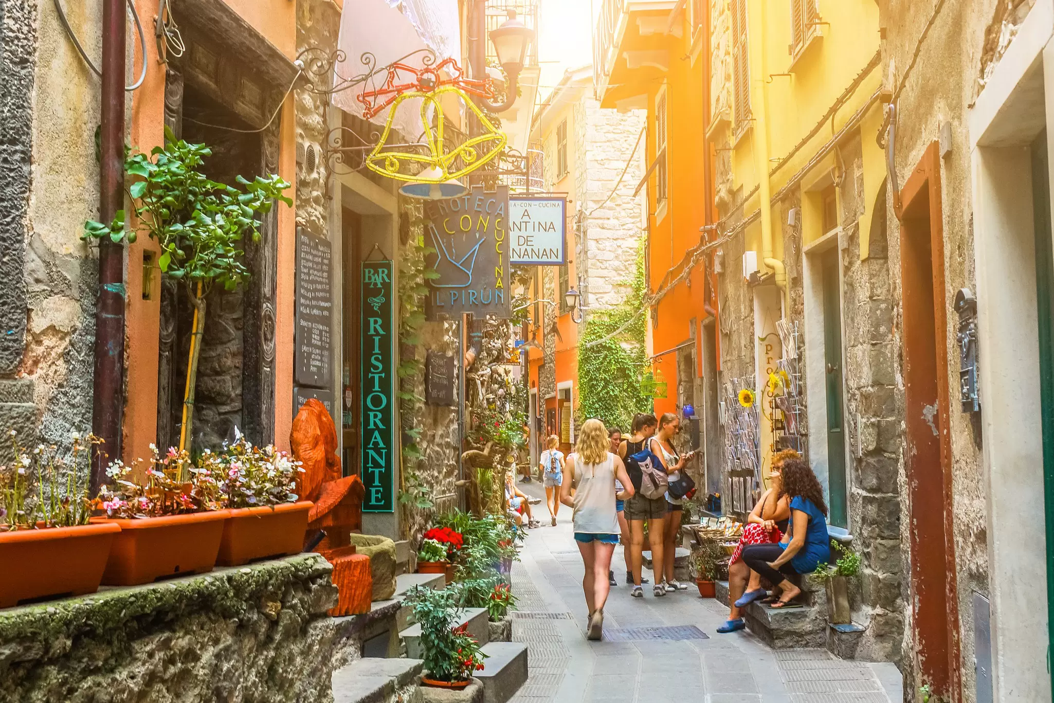 Tourists sitting and walking along a narrow colorful street on a sunny day