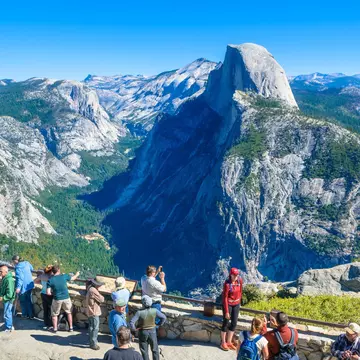 Visitors gather at Glacier Point with the Half Dome mountain in the background.