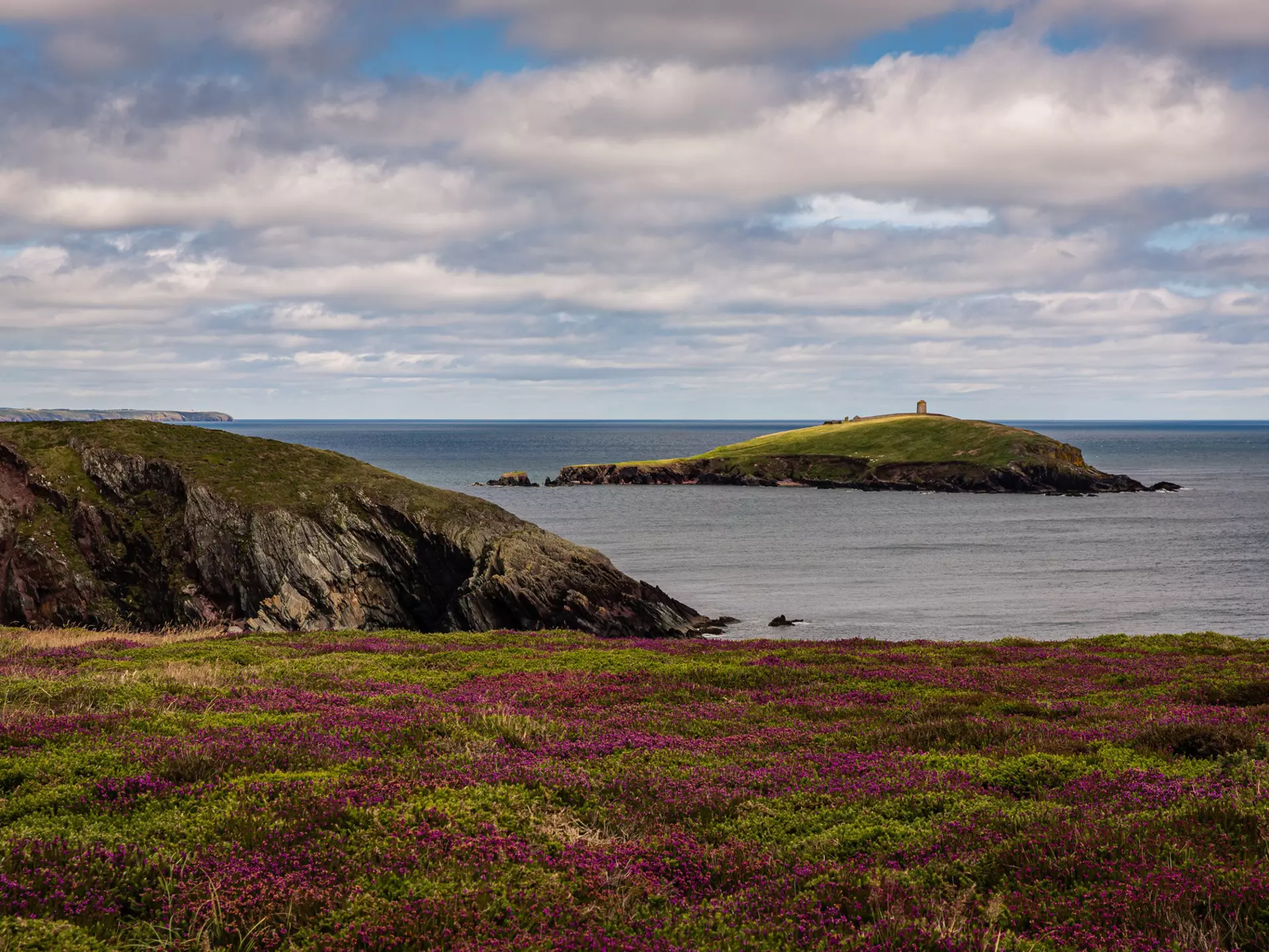 Colorful row houses with a towering cathedral in the background in the port town of Cobh, County Cork, Ireland. 