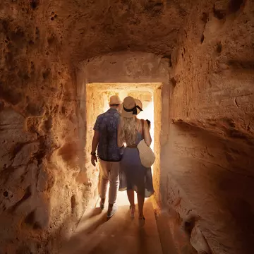 Man and woman walking through tunnel at the Tombs of the Kings
964890890