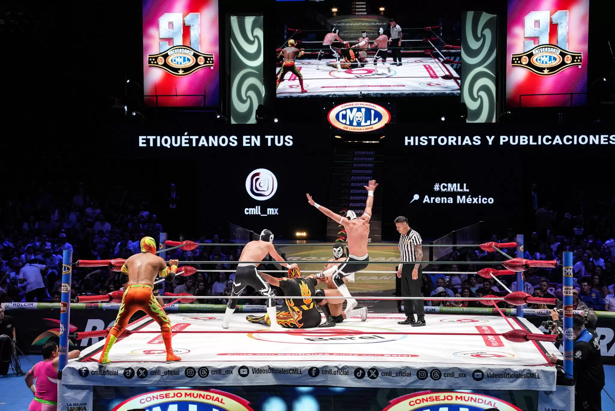 Several wrestlers in costume in a ring with a referee. 