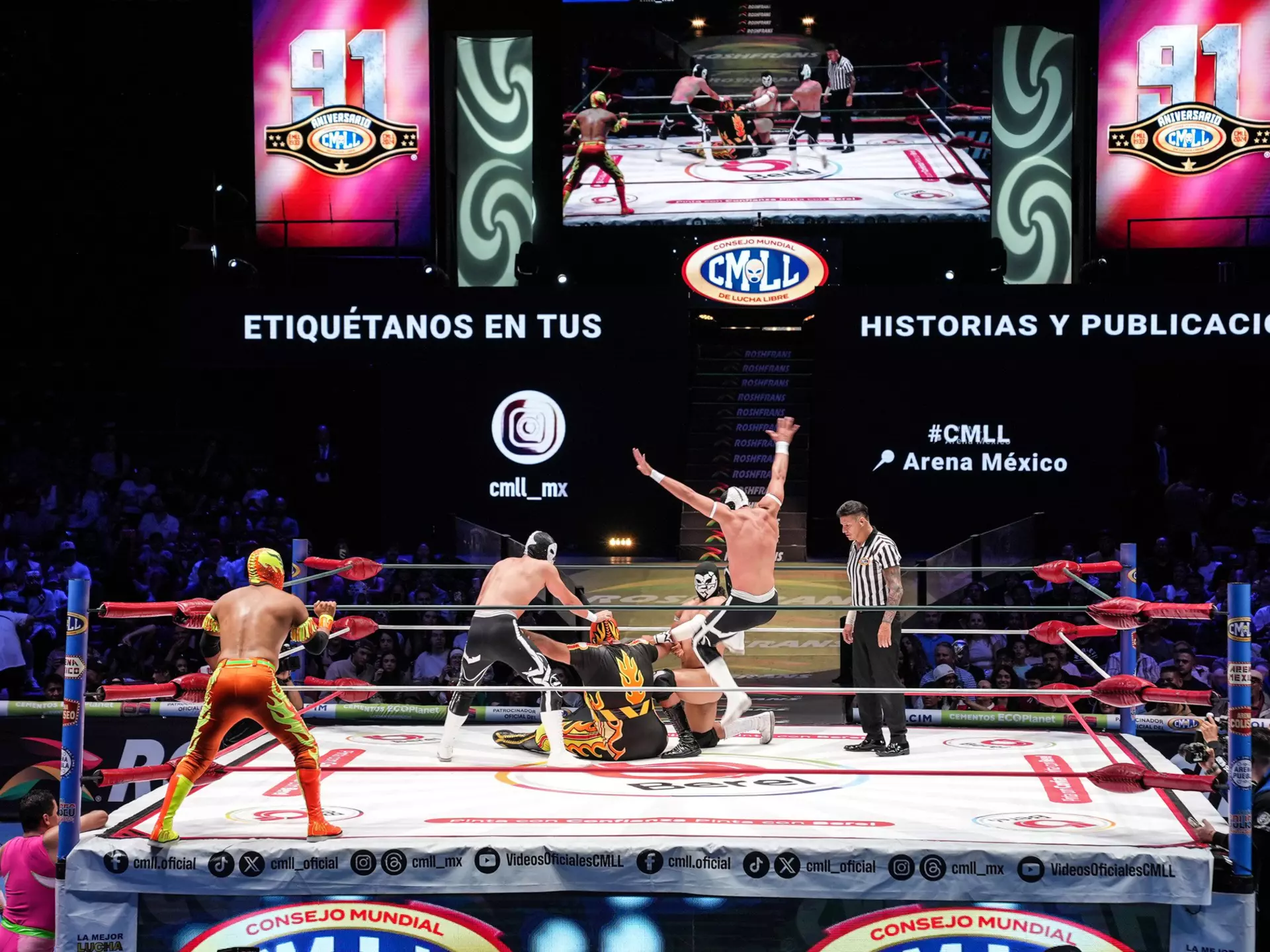 Several wrestlers in costume in a ring with a referee. 