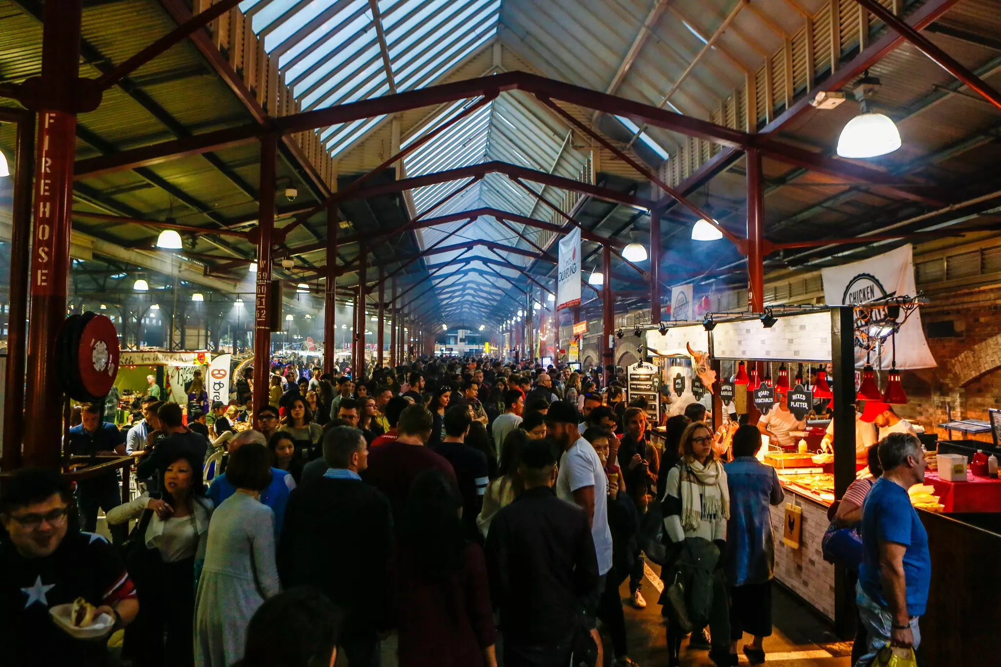 Crowds wander in Queen Victoria Market Melbourne, with steam from cooking at this popular landmark known for its food stalls