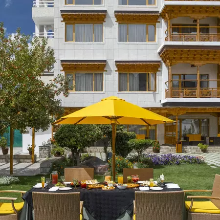 A yellow garden umbrella shades a brunch spread on the lawns at the Grand Dragon, Ladakh