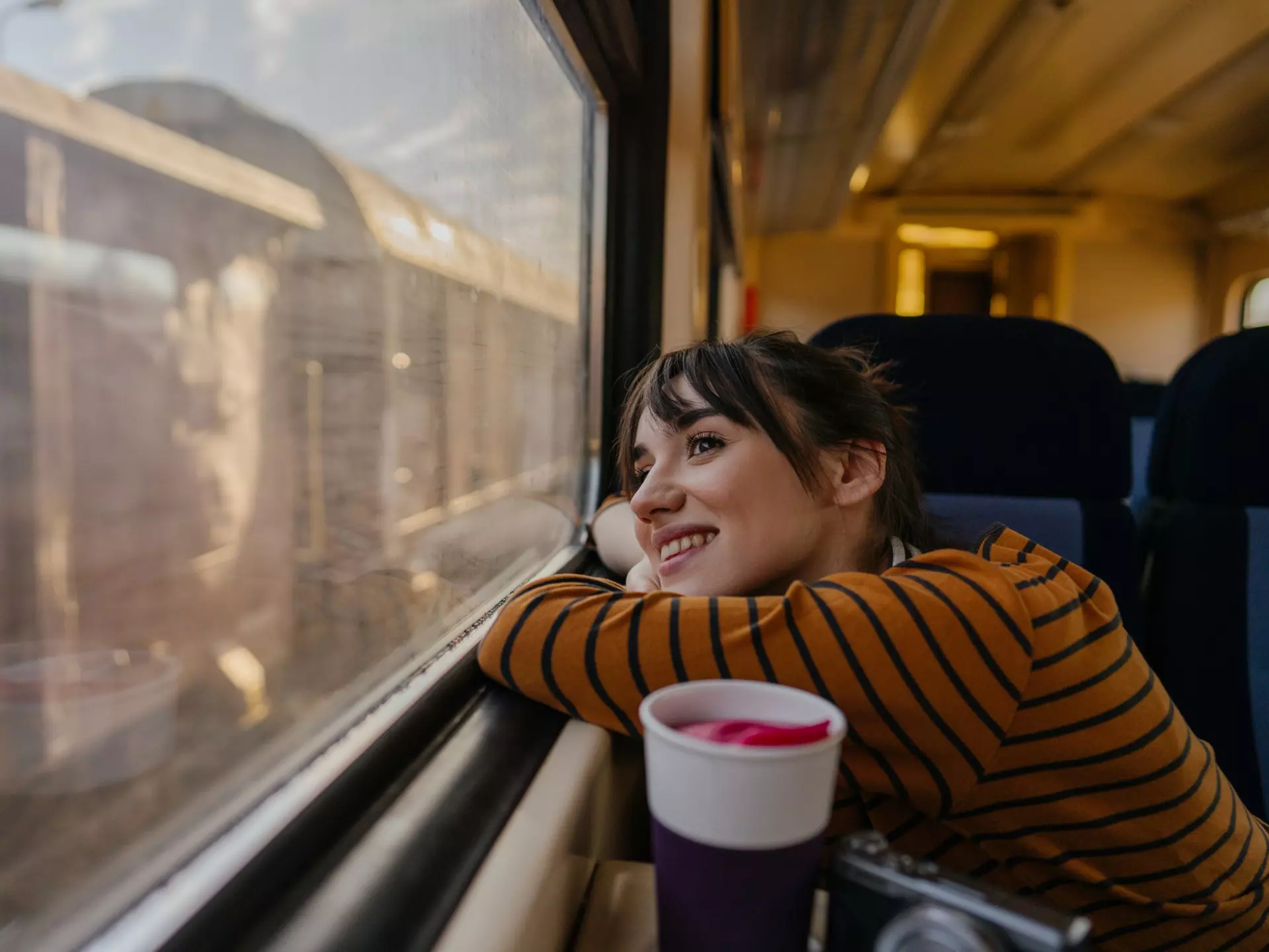 Photo of a young woman riding on a train, enjoying her trip while looking through the window
1254048612