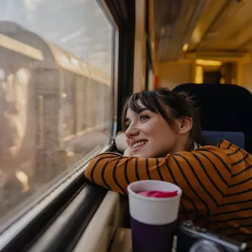 Photo of a young woman riding on a train, enjoying her trip while looking through the window
1254048612