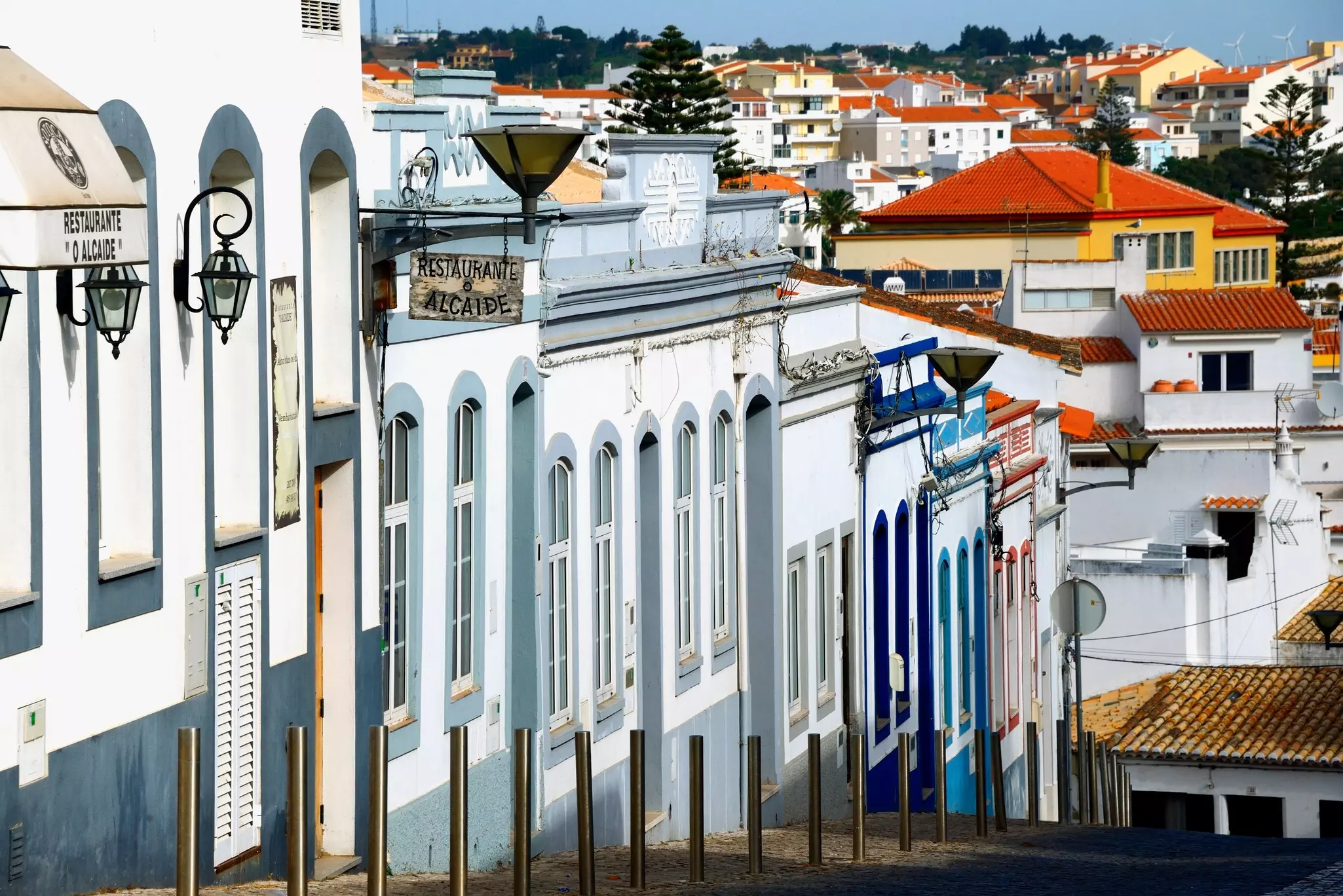 Painted buildings line a very steep city street in historic Lagos in the Algarve, Portugal.