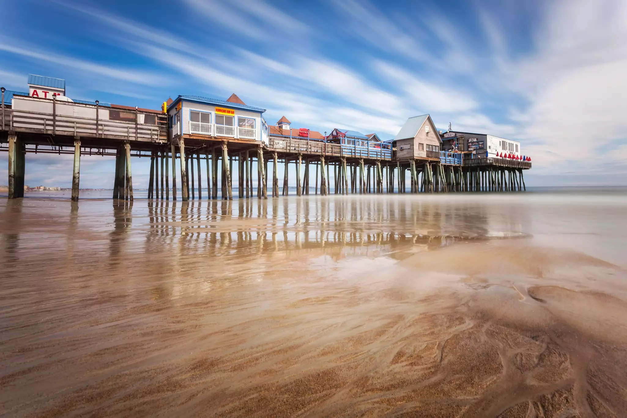 A low-tide sandy beach with tall pier of buildings on Orchard Beach, Maine.