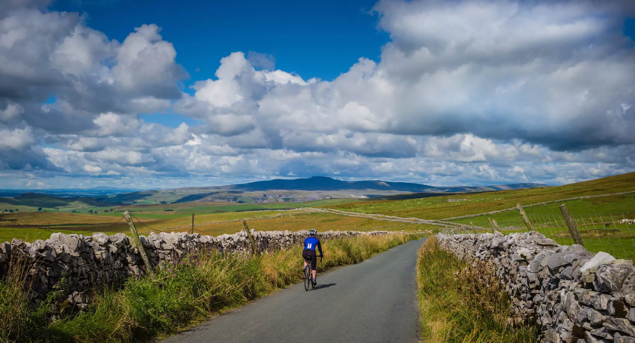 Female cyclist riding in the Yorkshire Dales National Park on the descent from Malham Moor towards Settle.