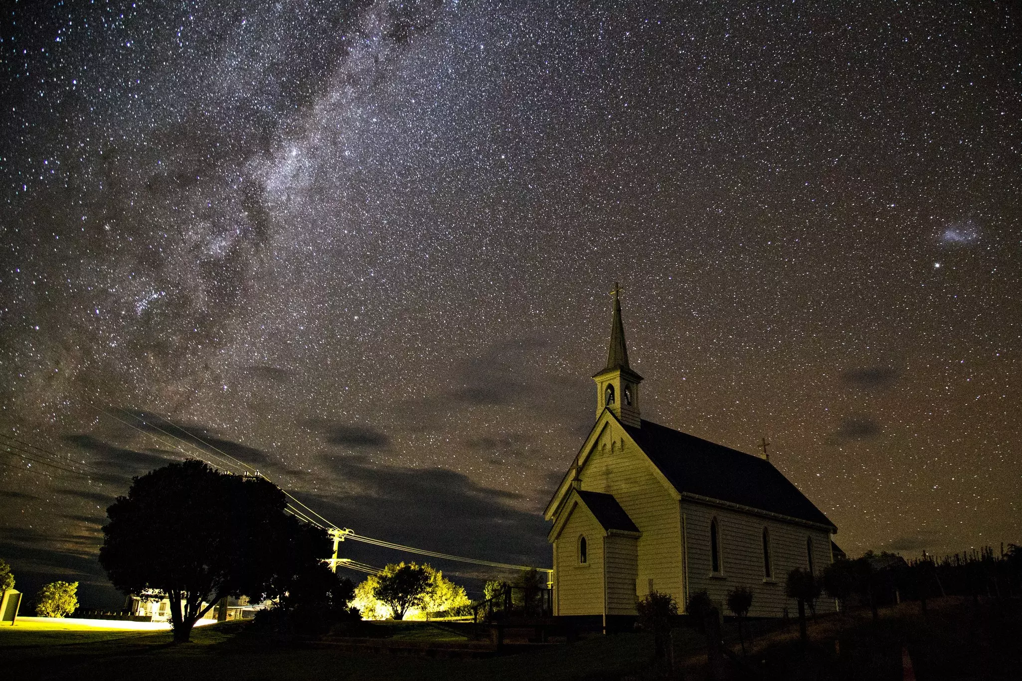 A small village church at night with a blanket of stars in the sky above