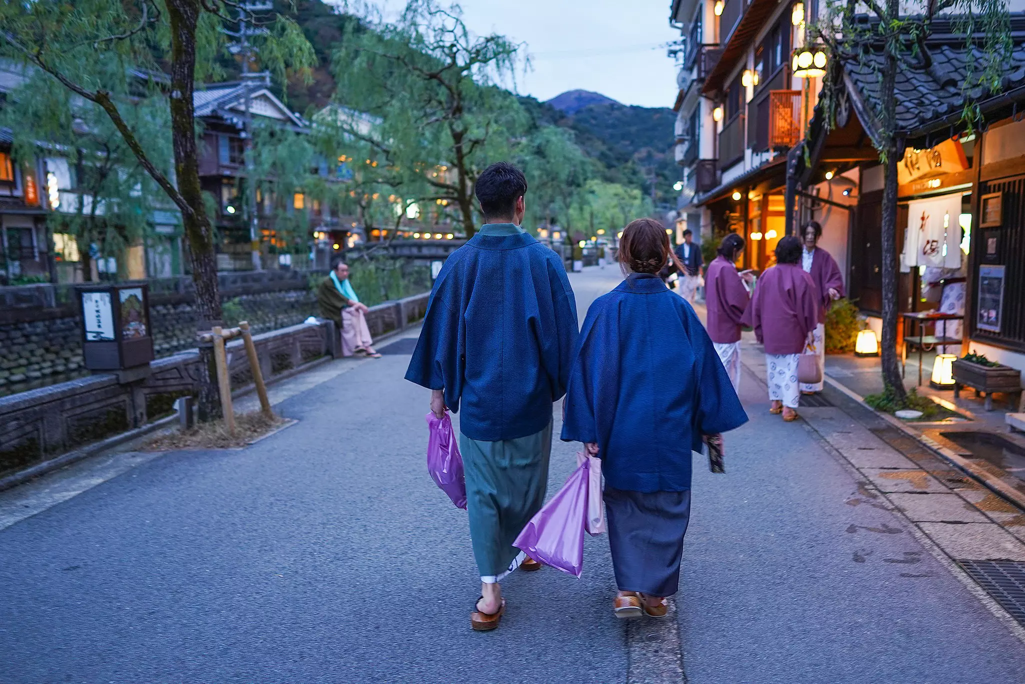 A couple wearing blue robes (yukata) while walking down a street