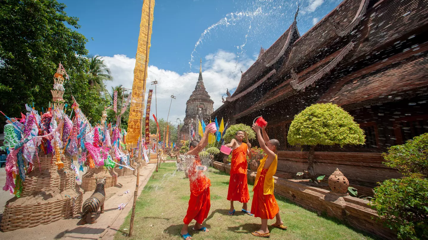 Monks splashing water Songkran Festival is celebrated in a traditional New Year's Day, A family comes to decorat tung in the temple Wat Phra singh in Chiang Mai,Thailand.  