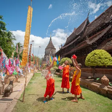 Monks splashing water Songkran Festival is celebrated in a traditional New Year's Day, A family comes to decorat tung in the temple Wat Phra singh in Chiang Mai,Thailand.  