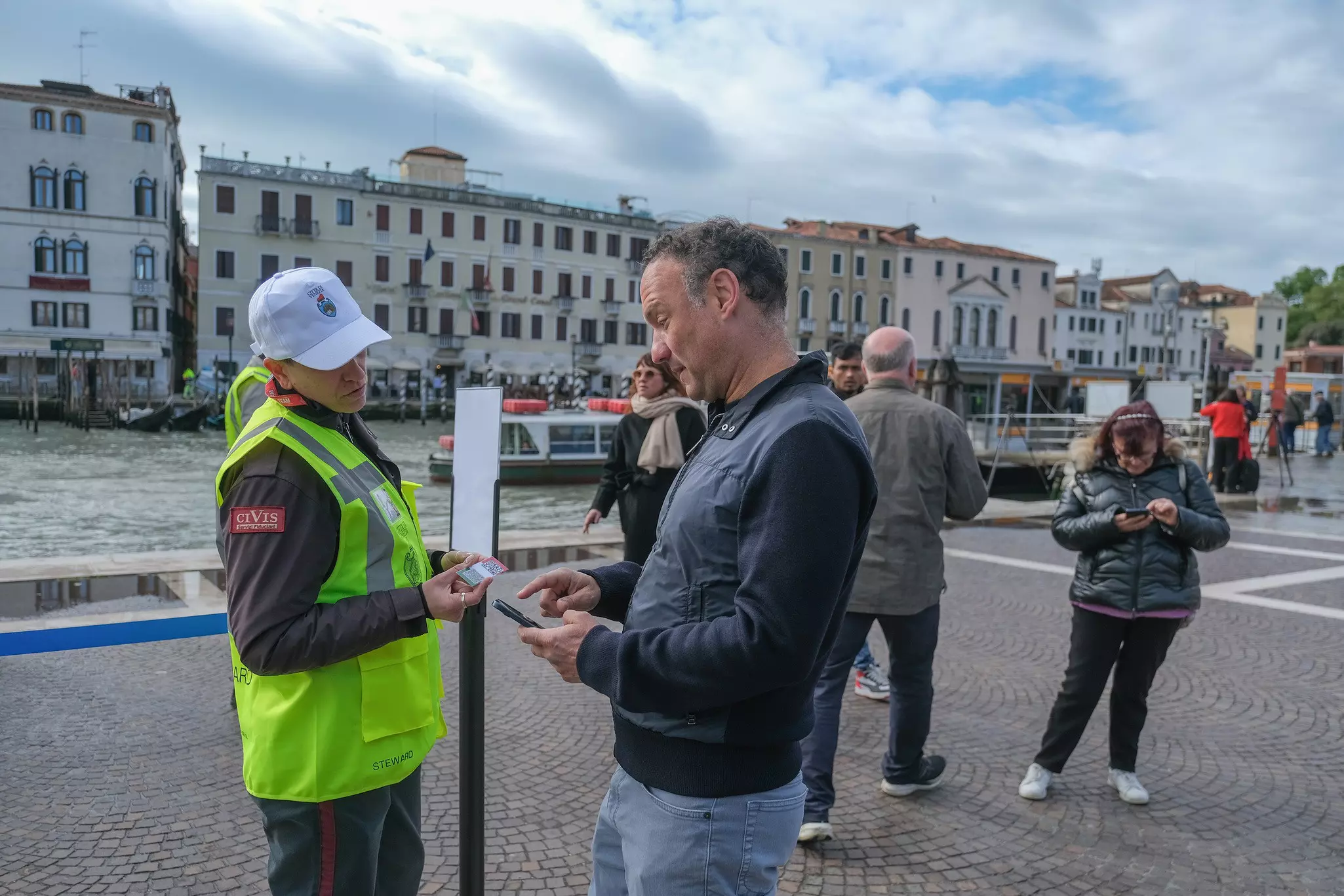 A steward checks a tourist's access ticket in Venice.