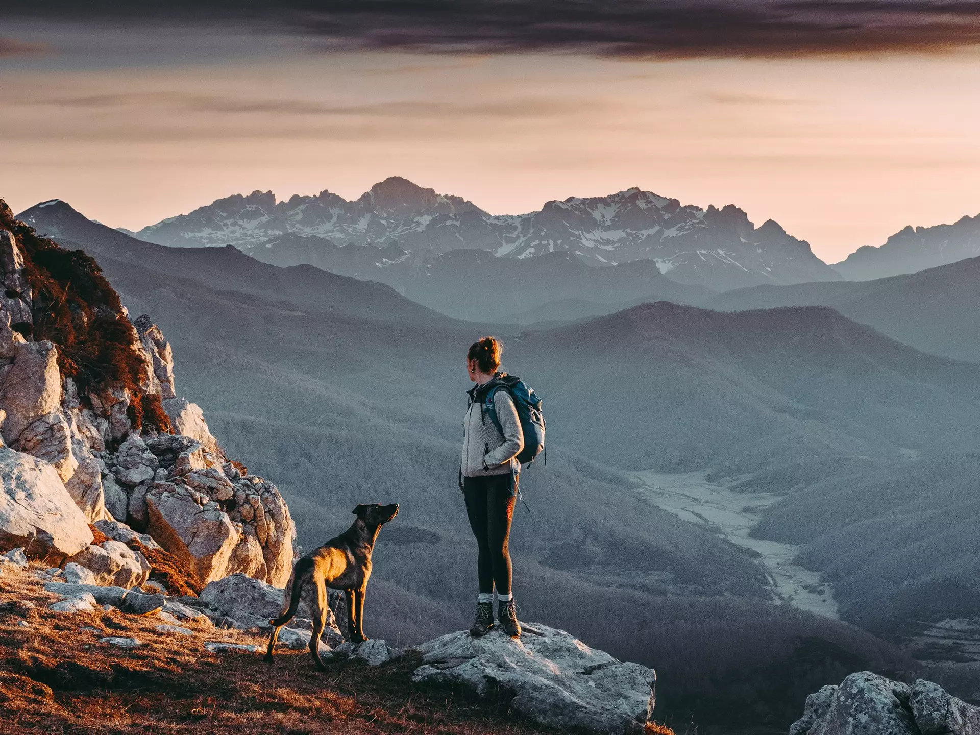 Woman hiking and looking at the view on the top of a mountain with a beautiful landscape at sunrise.
1316421598