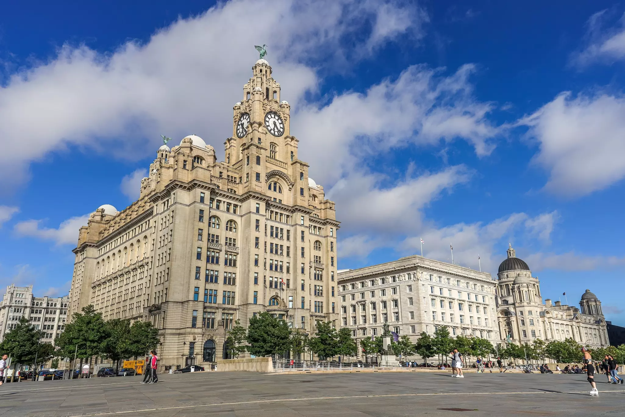 The Royal Liver Building, the Cunard Building and the Port of Liverpool Building with a few pedestrians nearby