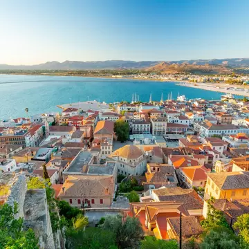 A view of sun-drenched homes with orange roofs against a seaside