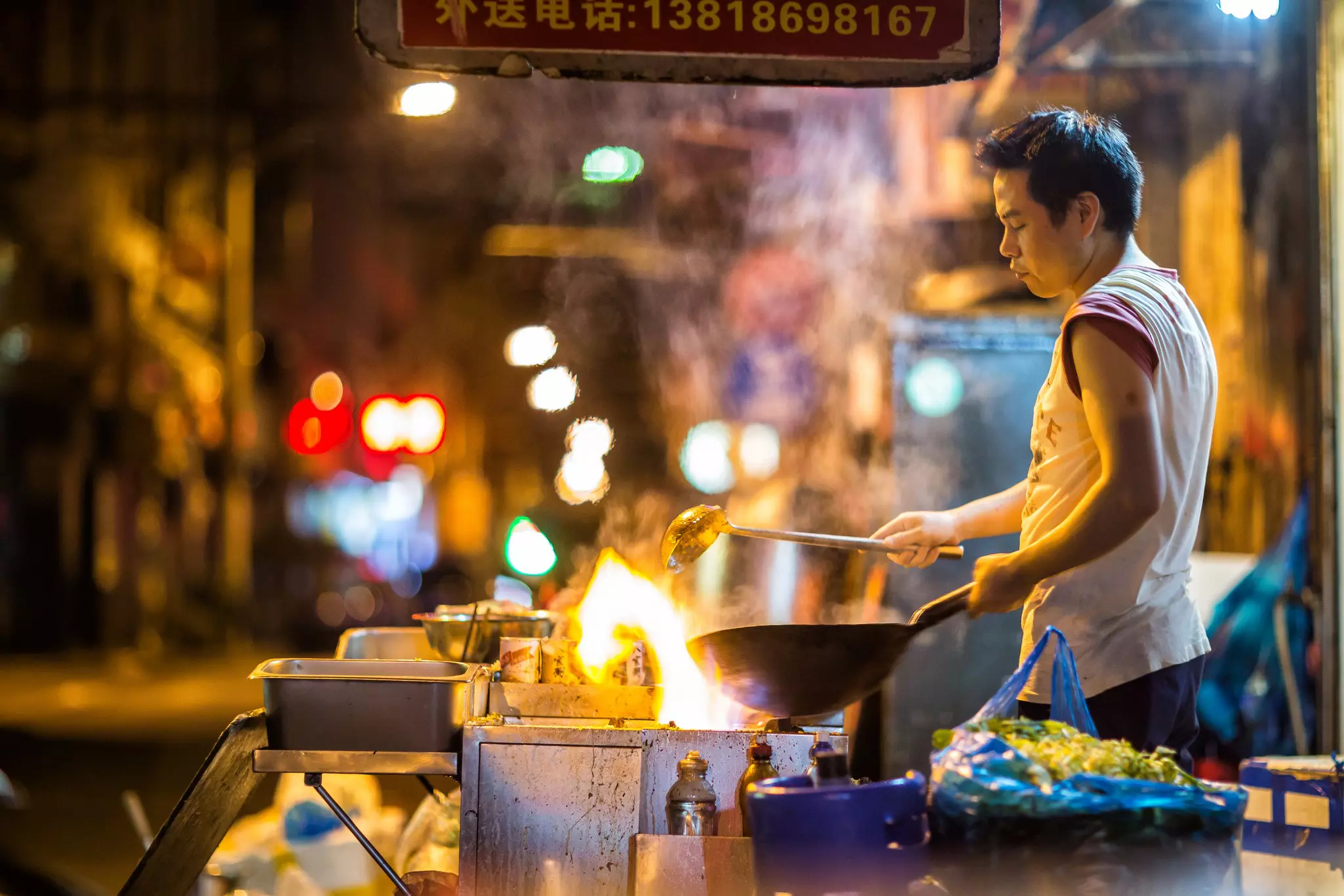 A man prepares food in a wok at a food stall in Shanghai, China.