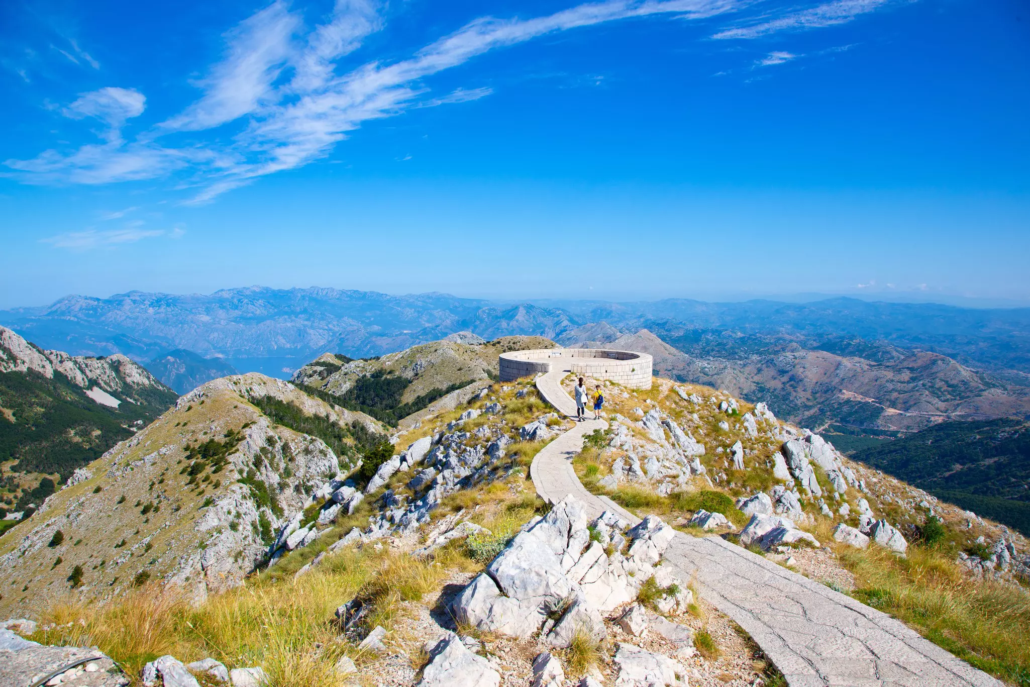 A path leads over a rocky hilltop to a viewpoint.