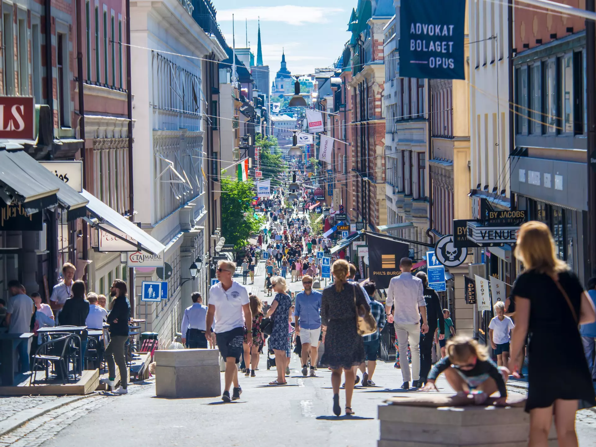 View of crowds of pedestrians on a central shopping street on a sunny day in Stockholm, Sweden.