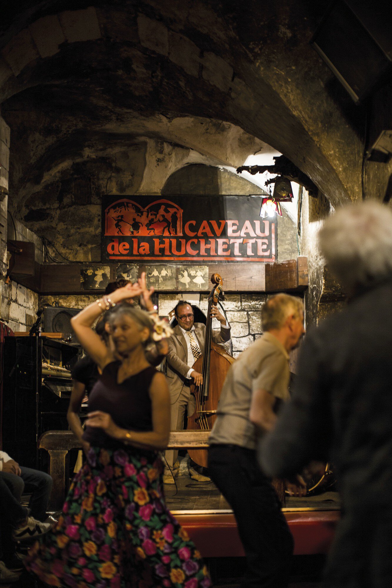 Swing dancers and a band. The band is in front of a red and black sign that says