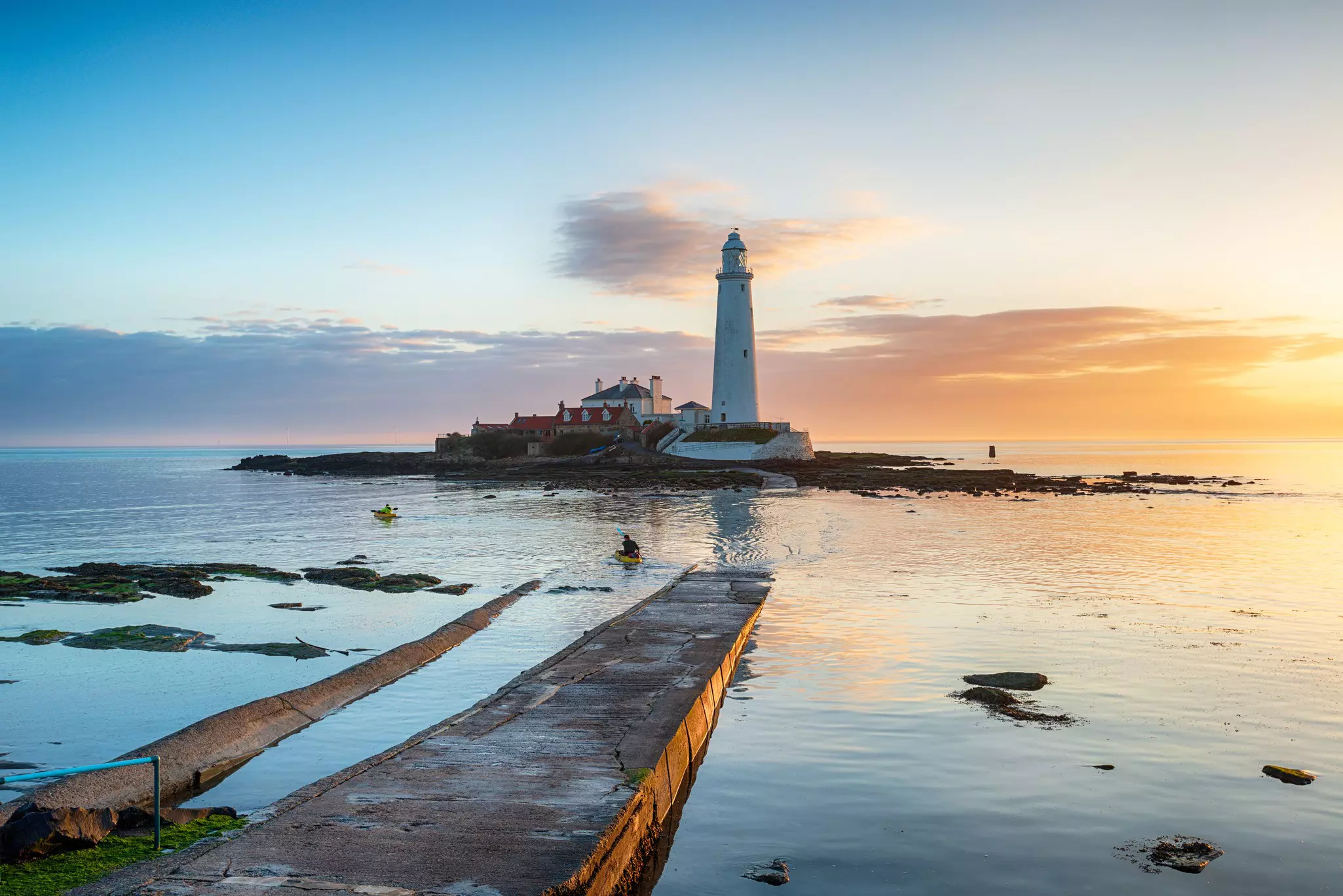 Kayakers paddle round the lighthouse at sunrise on St Mary's Island at Whitley Bay in Tyne and Wear on the Northumbria coast