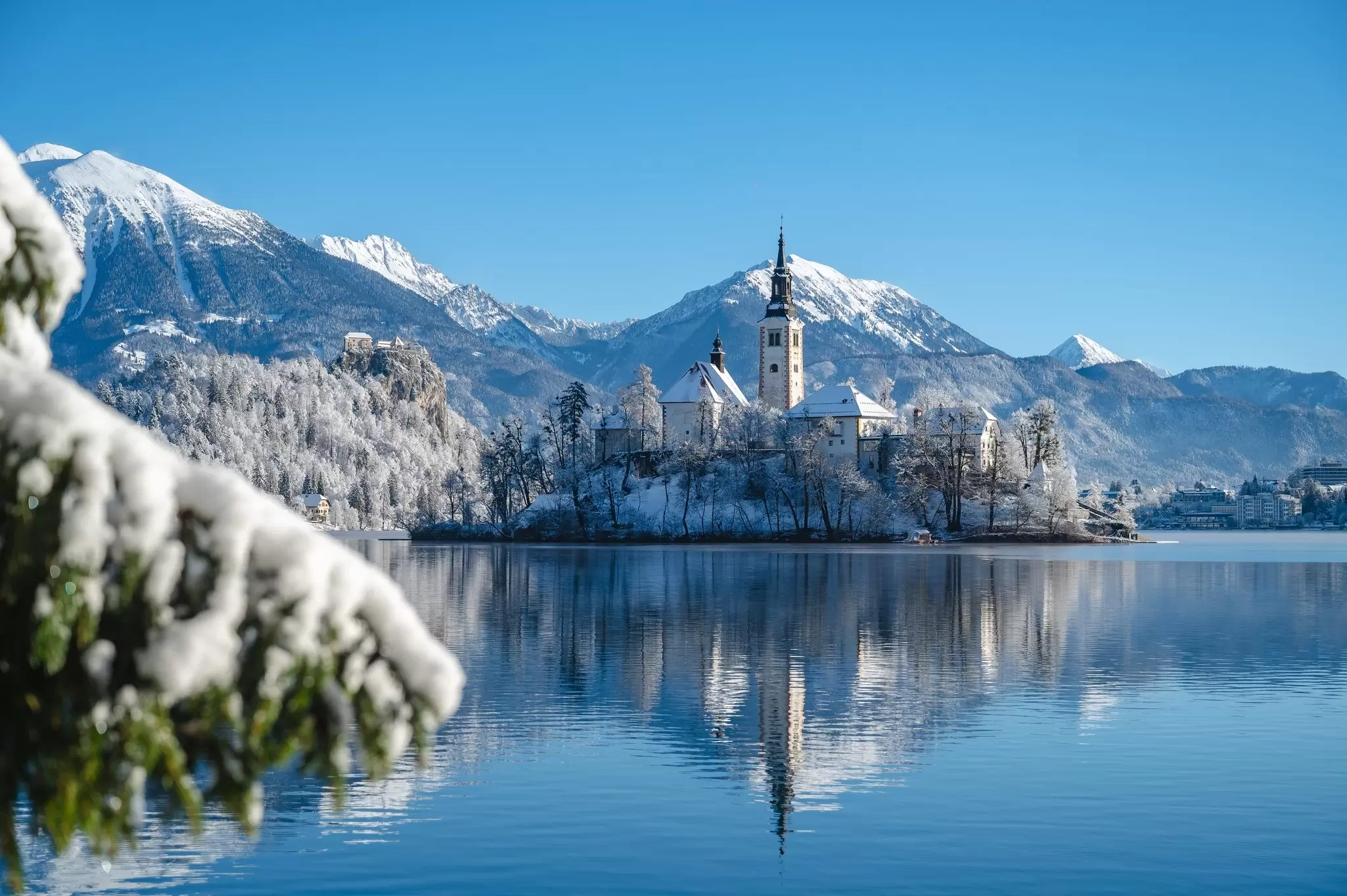 A church on an island in a lake in a snowy landscape.