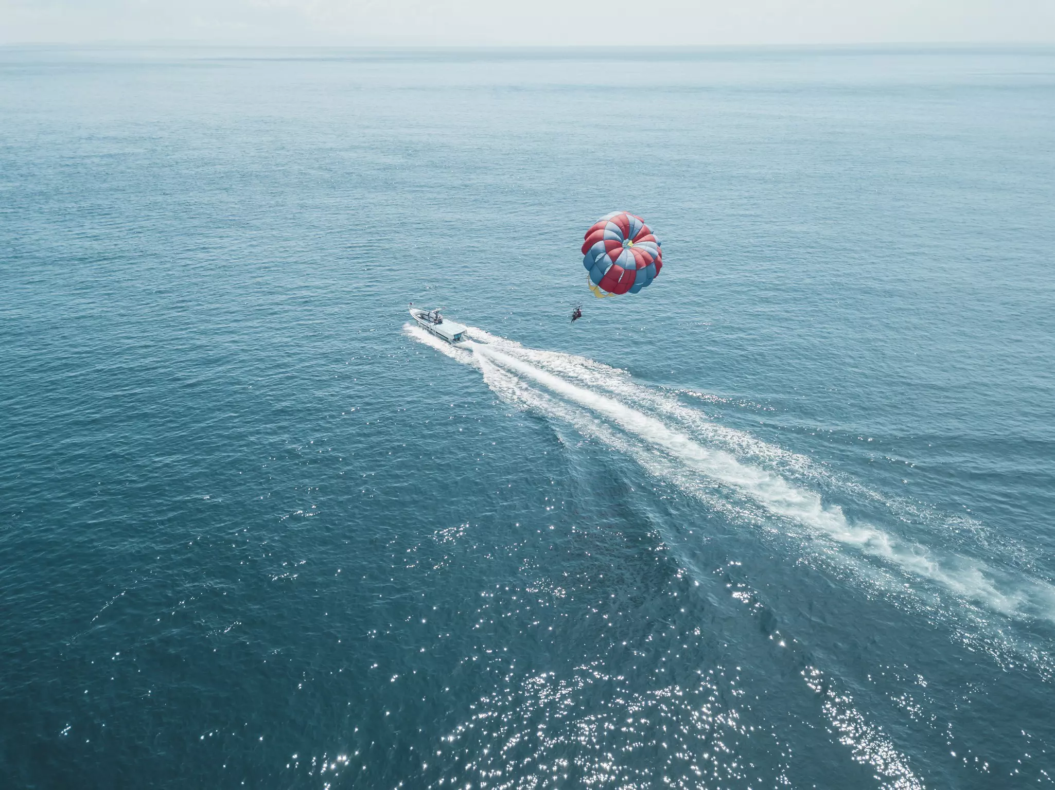 A motorboat pulling someone parasailing in the ocean
