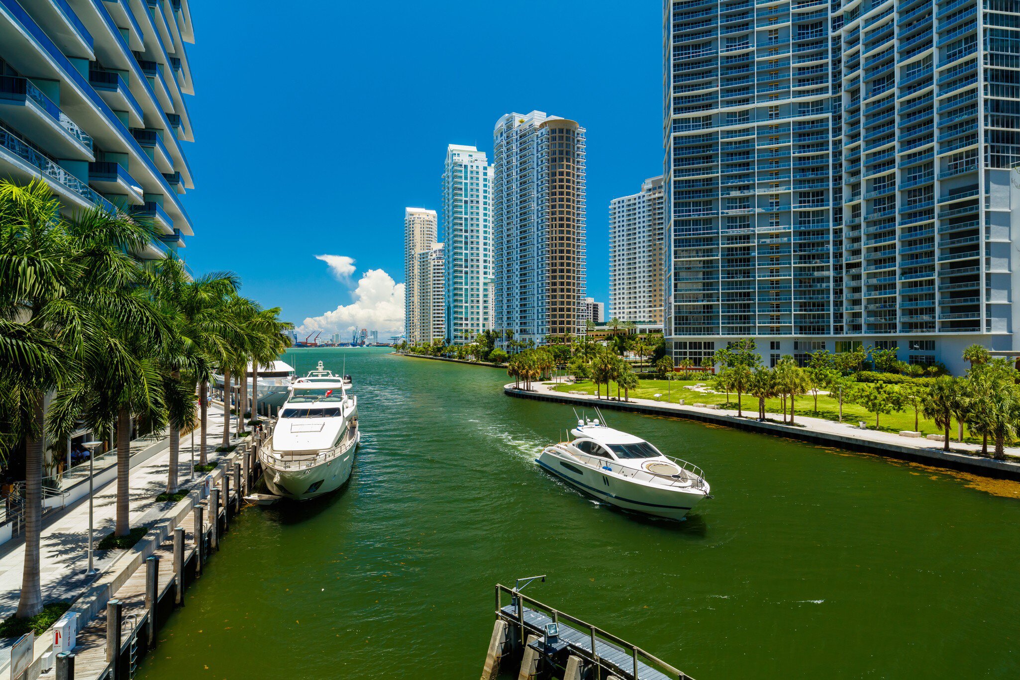 Downtown Miami along the Miami River inlet with Brickell Key in the background and yacht cruising by.