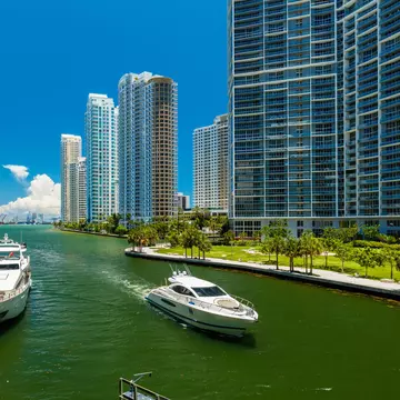 Downtown Miami along the Miami River inlet with Brickell Key in the background and yacht cruising by.