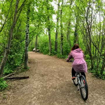 A photo of a woman enjoying a nice bike ride through the forest on a beautiful spring evening in the river valley of Edmonton, Alberta, Canada.