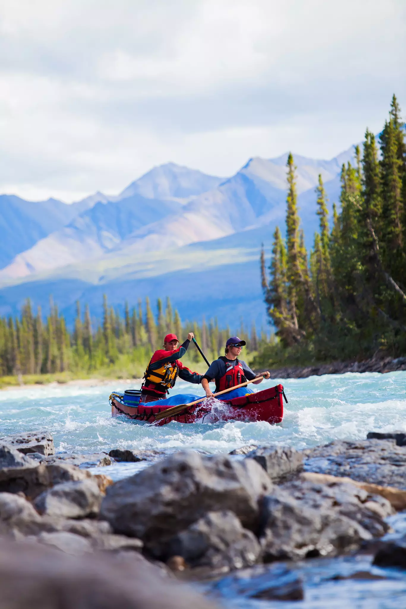 Two people paddle a canoe in a river in Northern Canada