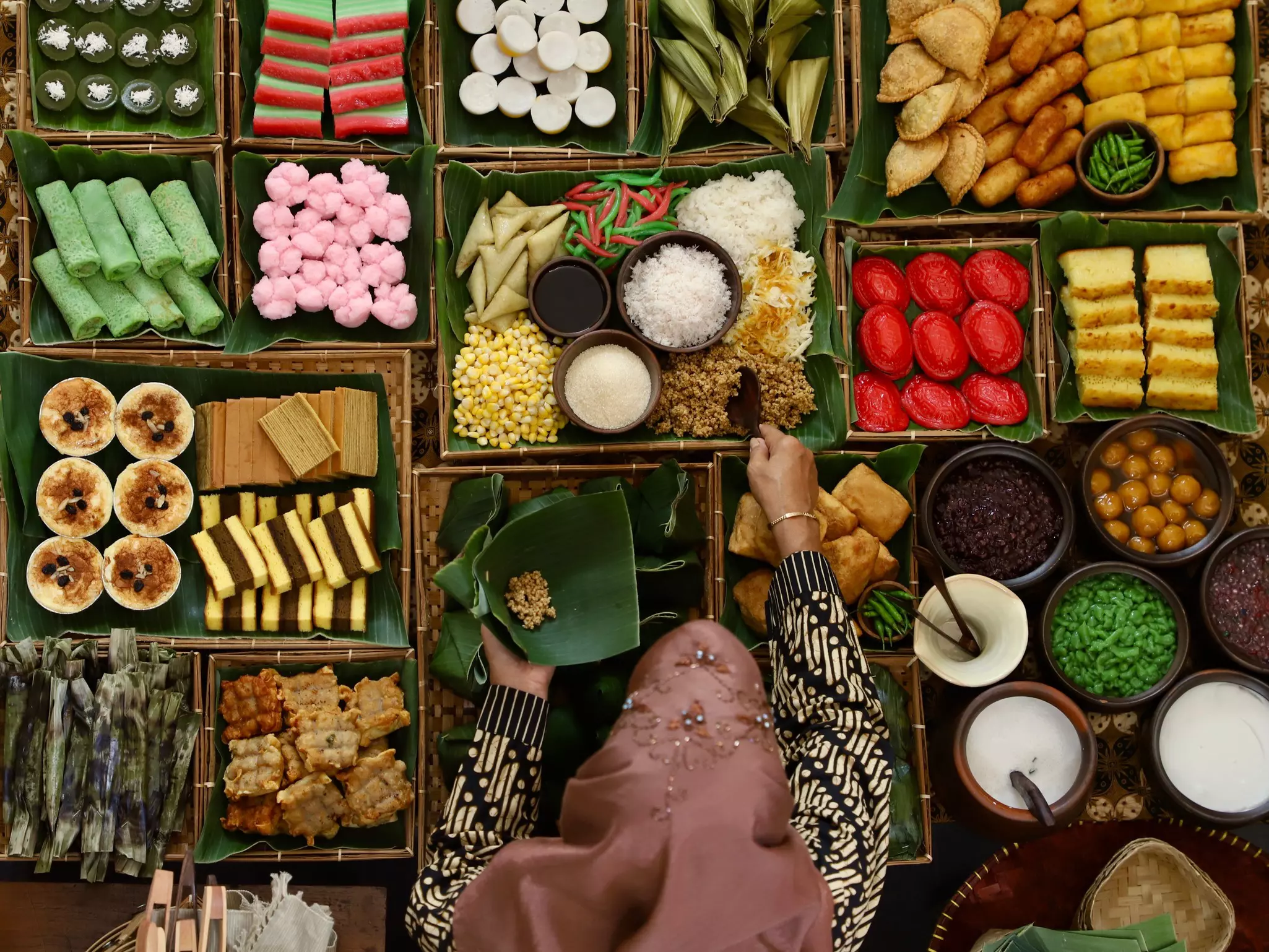 A food seller scooping tiwul at a market stall of Indonesian sweet and savory snacks