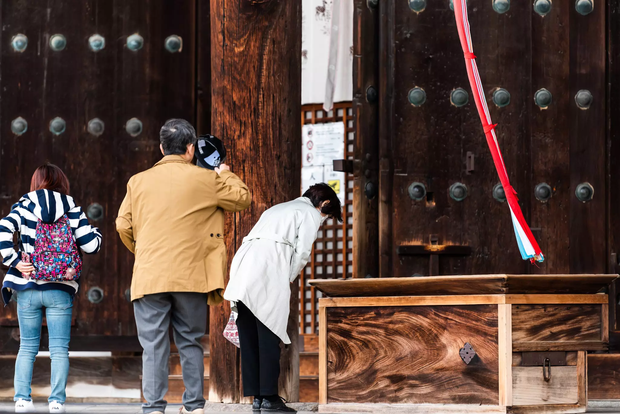 A woman bows in the sanctuary of a temple as a man looks on.