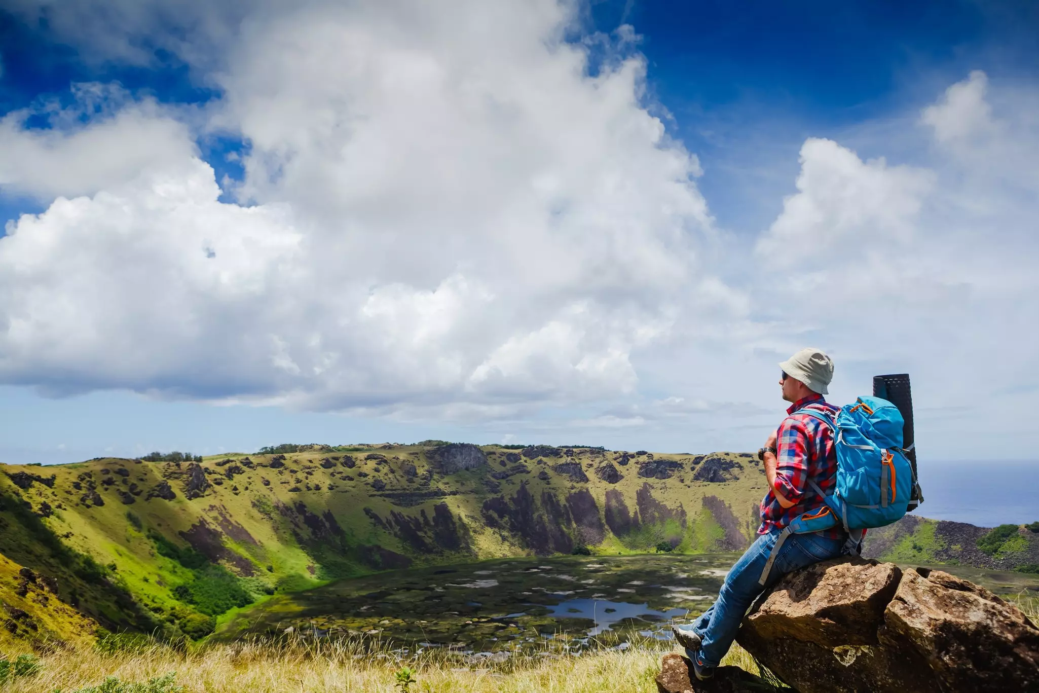 A hiker resting on the rim of the Rano Kau volcano, Rapa Nui (Easter island), Chile.