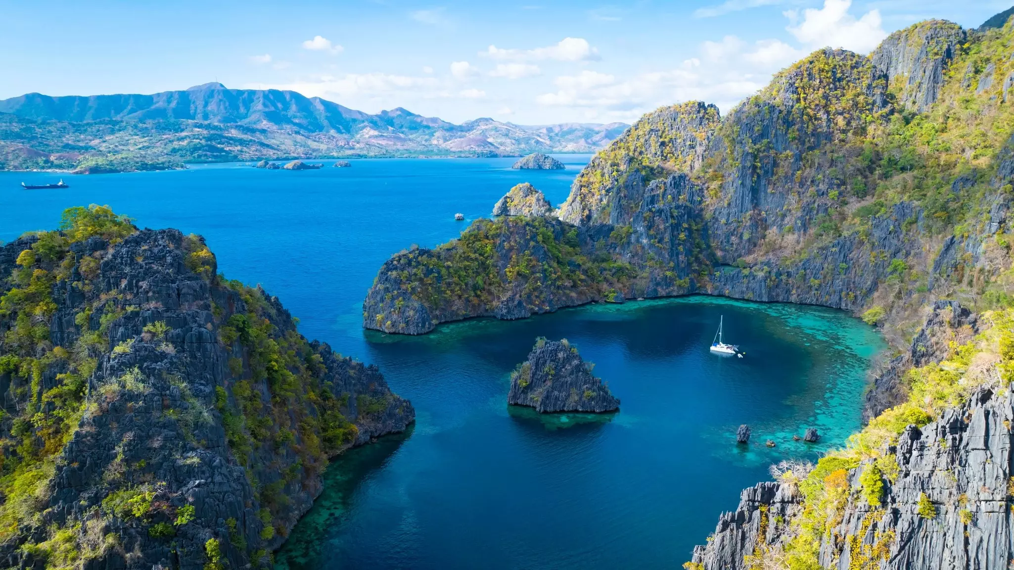 The Aerial view of white sand beach bathed by a crystal clear water. Entalula island, Bacuit Bay, El Nido, Palawan, Philippines.